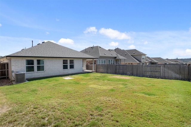 back of property featuring central AC and a lawn