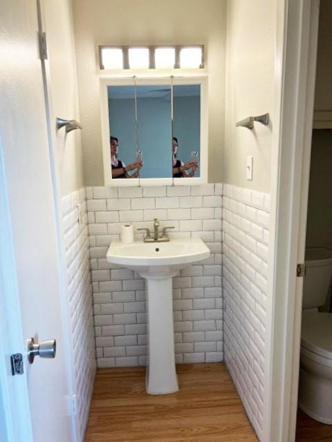 5608 Cougar Dr Unit 219, Austin, TX 78745 - bathroom featuring toilet, a wainscoted wall, wood finished floors, and tile walls