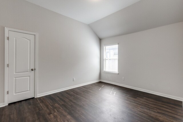 empty room with vaulted ceiling and dark hardwood / wood-style floors