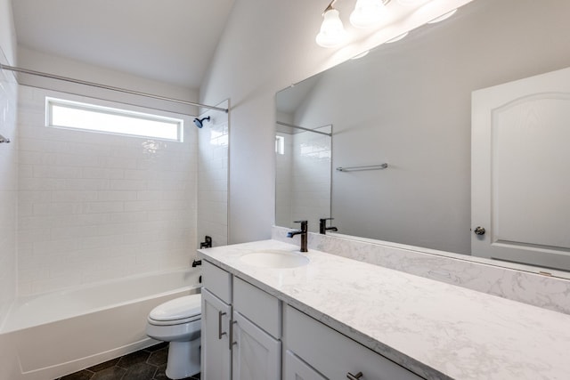 full bathroom with tiled shower / bath, vanity, vaulted ceiling, and toilet