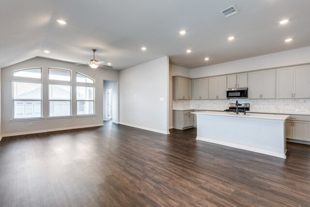 kitchen with a kitchen island with sink, dark hardwood / wood-style floors, ceiling fan, and tasteful backsplash