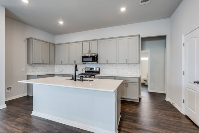 kitchen featuring stainless steel appliances, a center island with sink, dark wood-type flooring, and sink