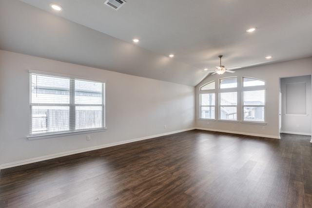 empty room with dark wood-type flooring, vaulted ceiling, ceiling fan, and a healthy amount of sunlight