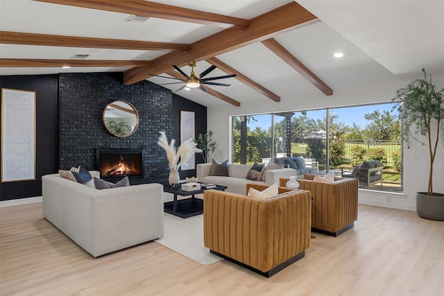 living room featuring ceiling fan, a fireplace, lofted ceiling with beams, and light wood-type flooring