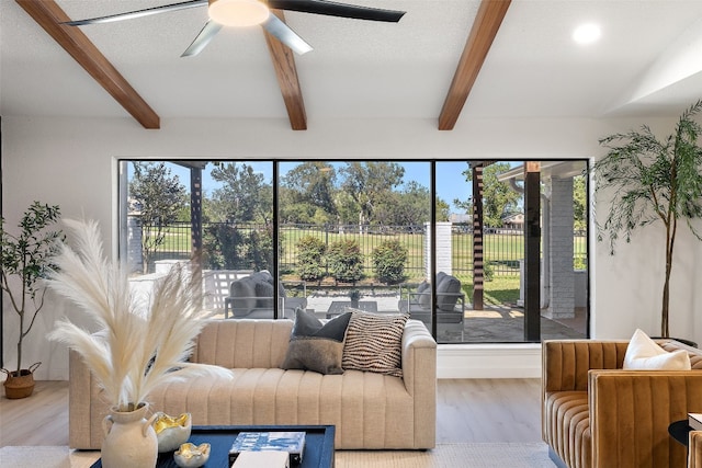 living room featuring ceiling fan, light hardwood / wood-style floors, a textured ceiling, and beam ceiling