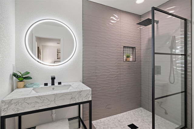 bathroom with tiled shower and sink