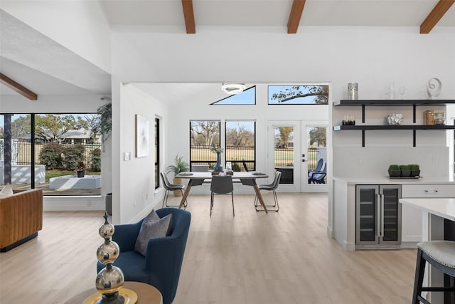 living room with wine cooler, beam ceiling, french doors, and light hardwood / wood-style flooring