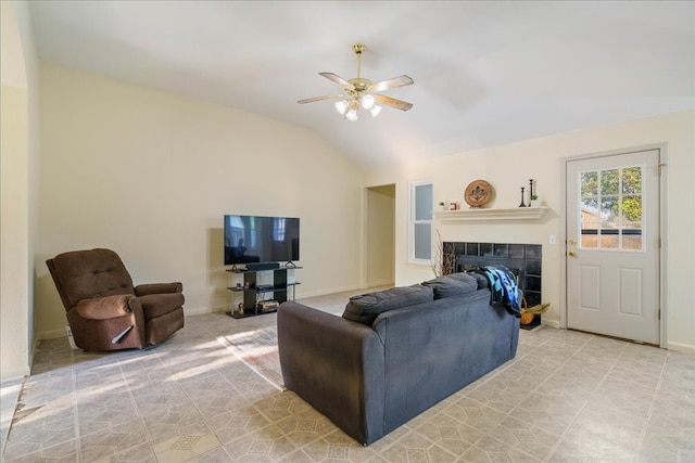 living room with lofted ceiling, ceiling fan, a tile fireplace, and light tile patterned floors