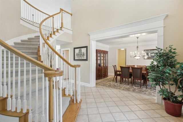 entryway featuring crown molding, light tile patterned floors, and an inviting chandelier