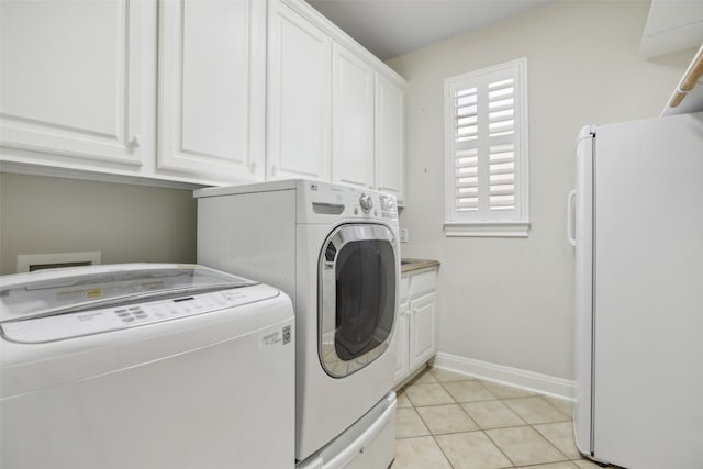 clothes washing area featuring washer and dryer, cabinets, and light tile patterned floors