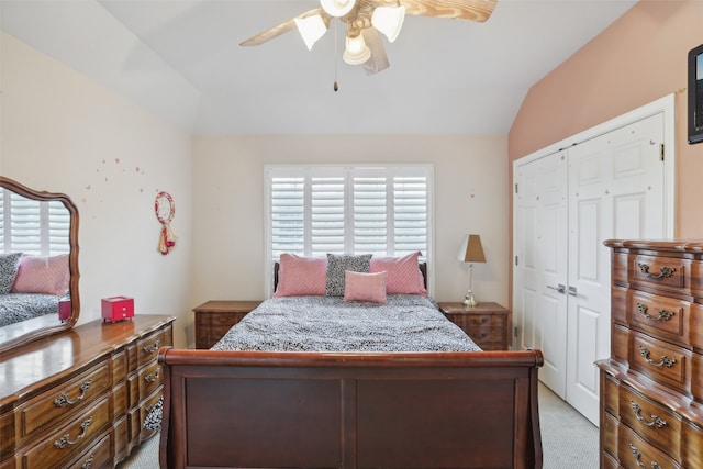 bedroom featuring ceiling fan, a closet, light carpet, and vaulted ceiling