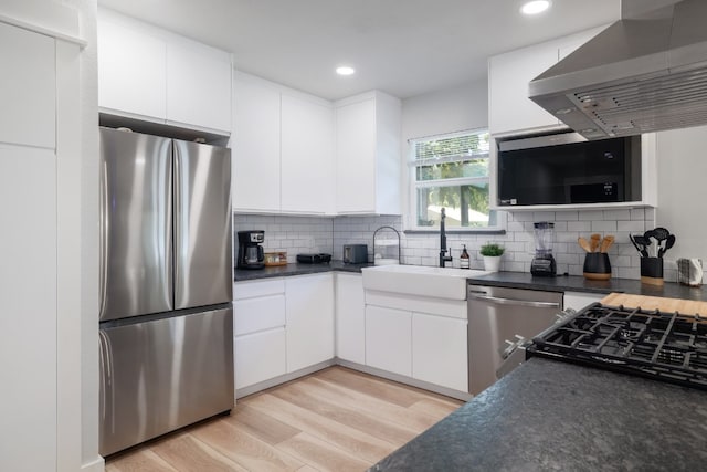 kitchen with white cabinetry, stainless steel appliances, light wood-type flooring, range hood, and sink