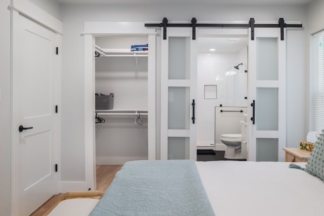 interior space featuring a barn door, light wood-type flooring, and ensuite bathroom