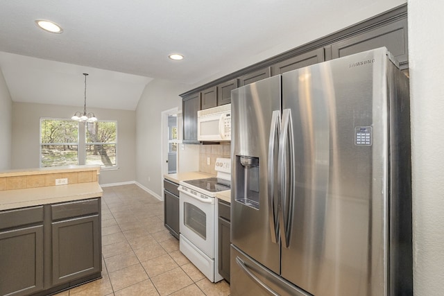 kitchen featuring hanging light fixtures, an inviting chandelier, vaulted ceiling, white appliances, and decorative backsplash