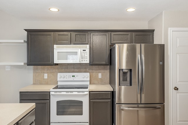 kitchen with tasteful backsplash, dark brown cabinets, and white appliances