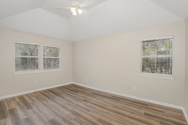 spare room featuring hardwood / wood-style floors, vaulted ceiling, and a healthy amount of sunlight