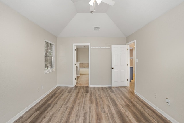 unfurnished bedroom with ceiling fan, hardwood / wood-style floors, ensuite bathroom, and lofted ceiling