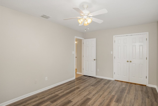 unfurnished bedroom with a closet, dark hardwood / wood-style floors, and ceiling fan