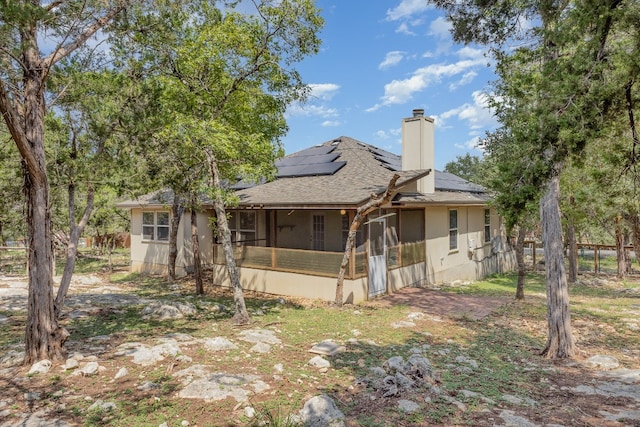 rear view of house with a sunroom and solar panels