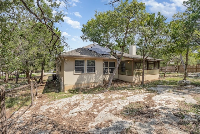 back of property with solar panels and a sunroom