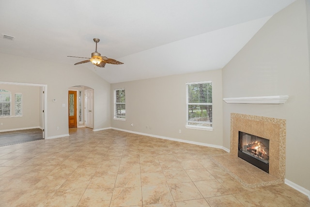 unfurnished living room featuring a wealth of natural light, ceiling fan, light tile patterned flooring, and vaulted ceiling