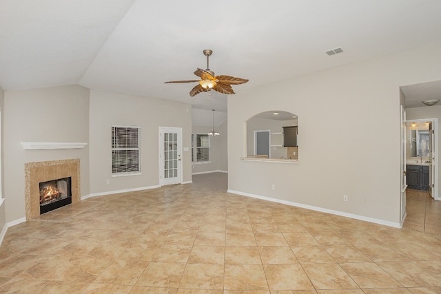 unfurnished living room with ceiling fan, light tile patterned floors, a tile fireplace, and vaulted ceiling