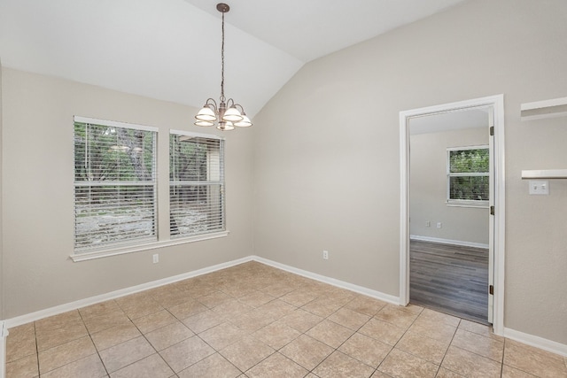 tiled empty room featuring an inviting chandelier, vaulted ceiling, and a healthy amount of sunlight