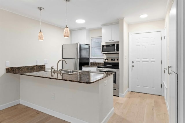 kitchen with light wood-type flooring, sink, white cabinets, kitchen peninsula, and appliances with stainless steel finishes