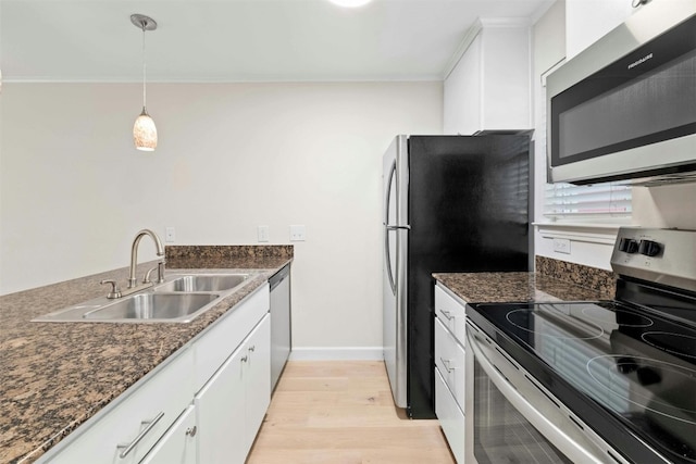 kitchen with appliances with stainless steel finishes, decorative light fixtures, light hardwood / wood-style flooring, and white cabinets