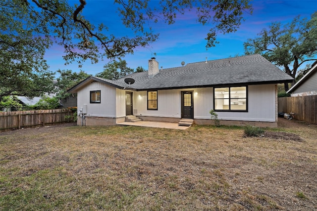 back house at dusk featuring a yard