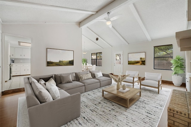 living room featuring ceiling fan, vaulted ceiling with beams, a textured ceiling, and hardwood / wood-style floors