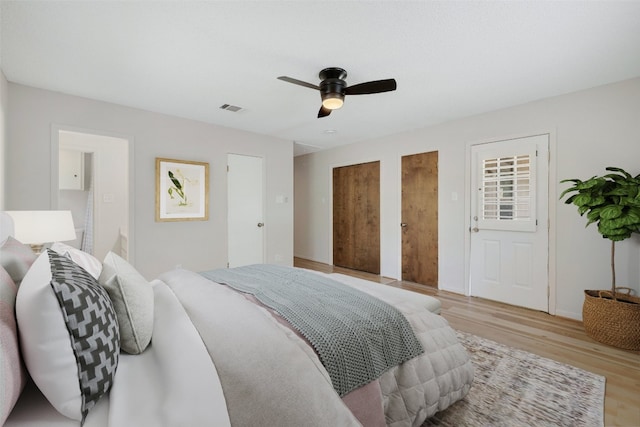 bedroom featuring light wood-type flooring, two closets, and ceiling fan