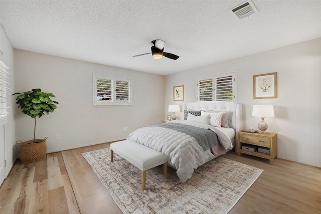 bedroom with a textured ceiling, ceiling fan, and light hardwood / wood-style flooring