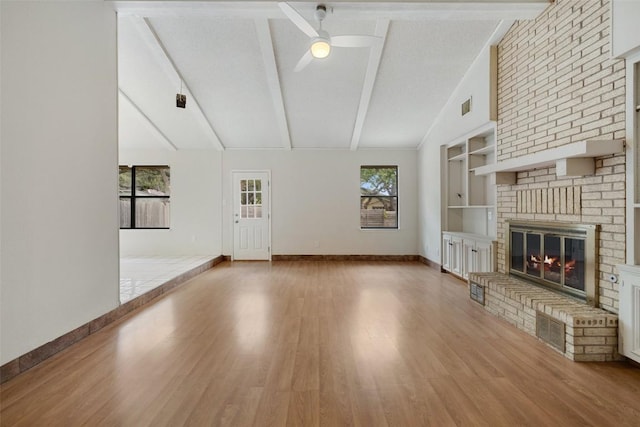 6700 Colina Ln, Austin, TX 78759 - unfurnished living room with a ceiling fan, a brick fireplace, wood finished floors, beam ceiling, and high vaulted ceiling