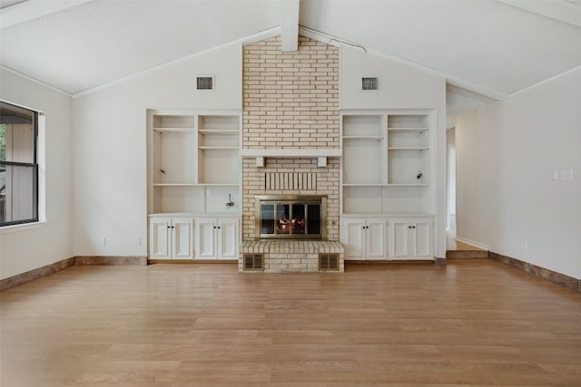 unfurnished living room featuring a brick fireplace, a textured ceiling, light hardwood / wood-style flooring, vaulted ceiling with beams, and built in shelves