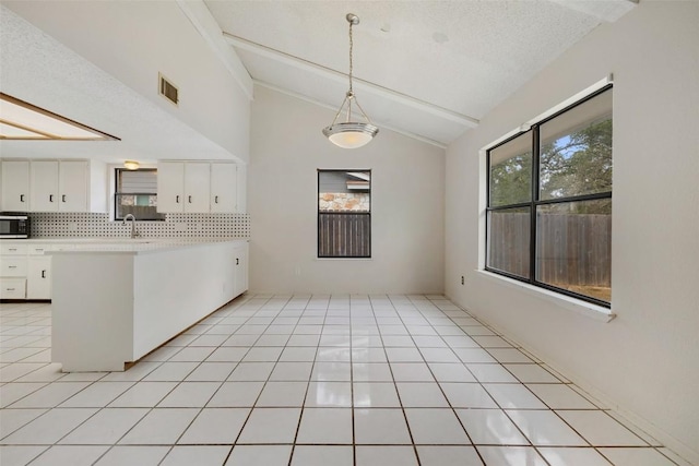 6700 Colina Ln, Austin, TX 78759 - kitchen with stainless steel microwave, white cabinets, light countertops, a peninsula, and tasteful backsplash
