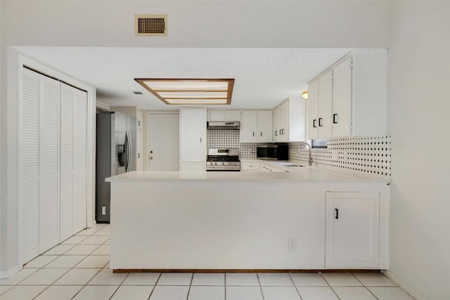 6700 Colina Ln, Austin, TX 78759 - kitchen featuring appliances with stainless steel finishes, light countertops, a peninsula, decorative backsplash, and light tile patterned flooring