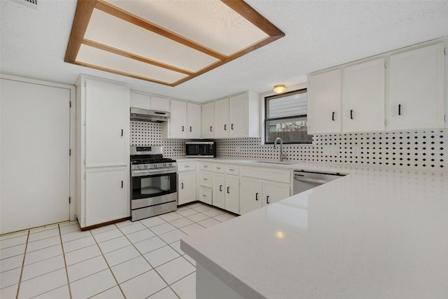 6700 Colina Ln, Austin, TX 78759 - kitchen with stainless steel appliances, under cabinet range hood, backsplash, light countertops, and light tile patterned floors