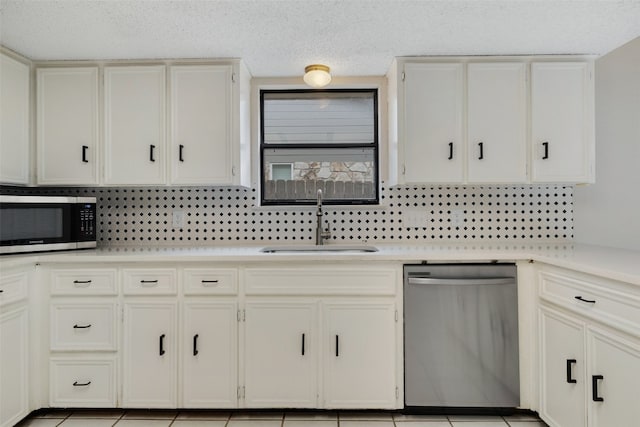 kitchen featuring sink, light tile patterned floors, stainless steel appliances, and white cabinets