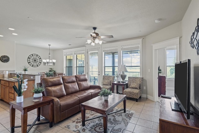 living room featuring ceiling fan with notable chandelier, a textured ceiling, light tile patterned flooring, and sink