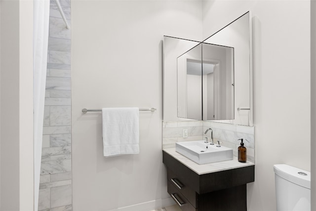 bathroom featuring toilet, vanity, and tasteful backsplash