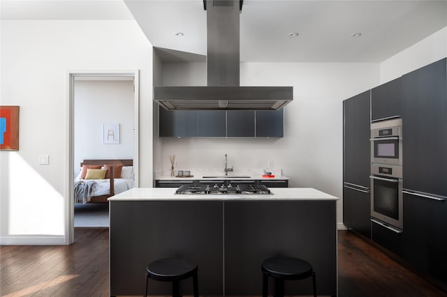 kitchen with a kitchen bar, sink, appliances with stainless steel finishes, and island exhaust hood