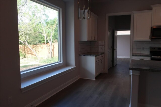 kitchen with appliances with stainless steel finishes, backsplash, white cabinetry, and hanging light fixtures