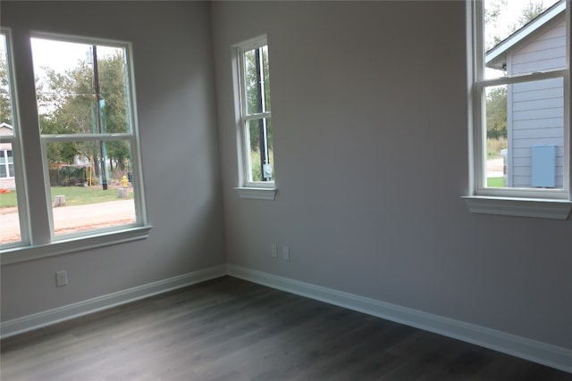 spare room featuring a healthy amount of sunlight and dark wood-type flooring