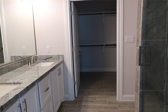 bathroom with a shower with shower door and vanity