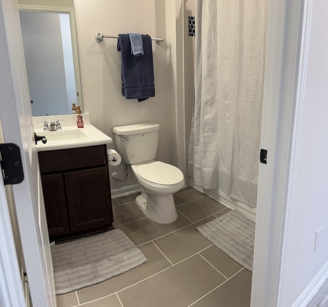 bathroom with a shower with curtain, vanity, toilet, and tile patterned floors