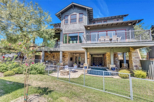 rear view of house featuring ceiling fan, a balcony, a yard, and a patio area