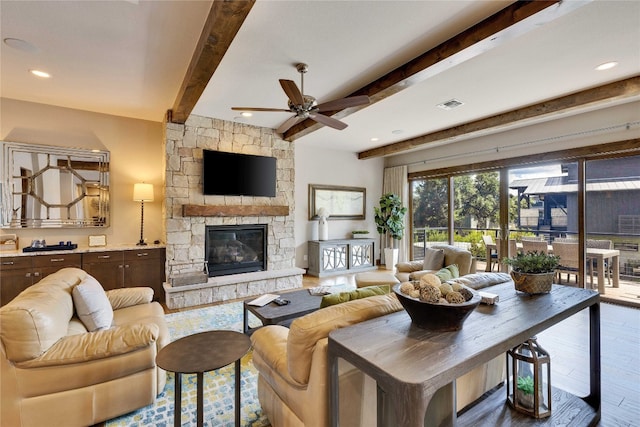 living room with hardwood / wood-style floors, ceiling fan, beamed ceiling, and a fireplace