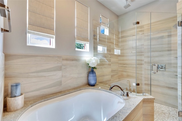 bathroom featuring plus walk in shower and tile walls