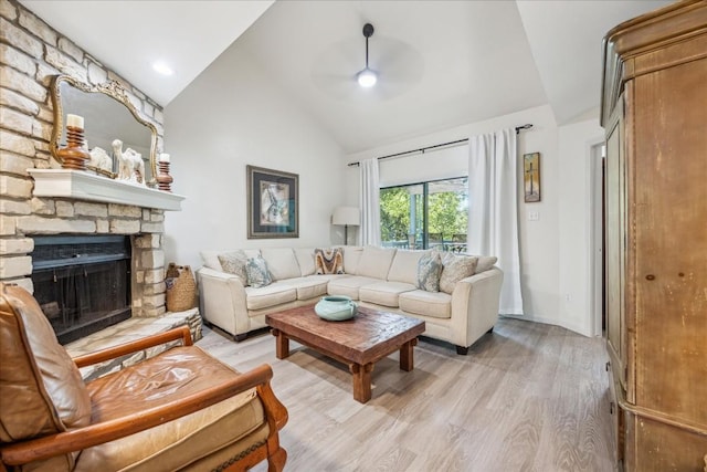 living room with ceiling fan, high vaulted ceiling, a fireplace, and light hardwood / wood-style floors